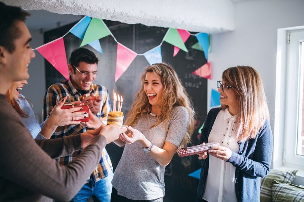 Colleagues surprise a woman with cake on her birthday at work