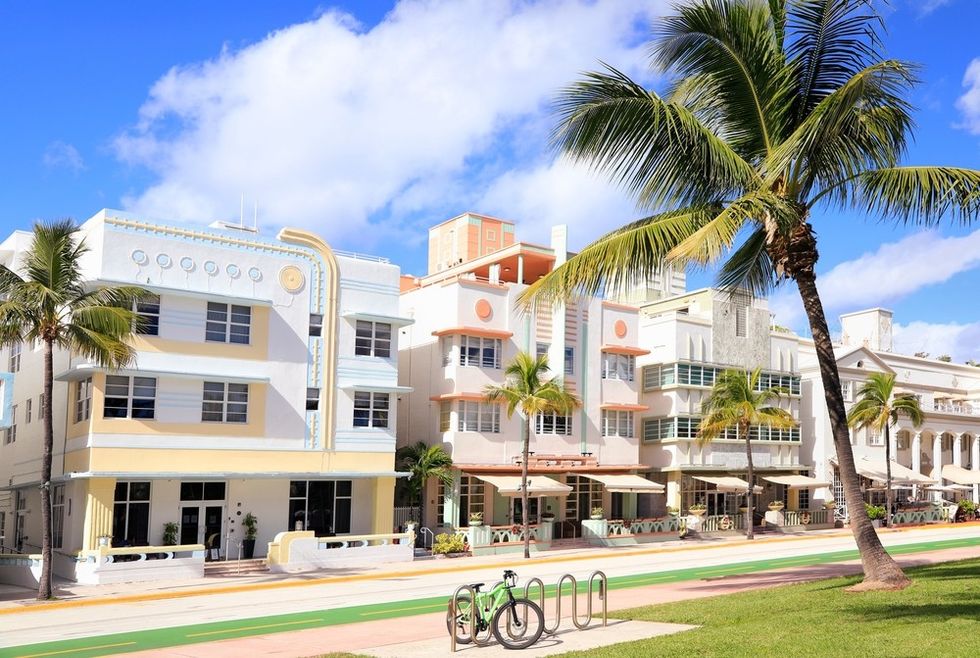 Colorful Art Deco buildings, palm trees, and a bike on a sunny day.