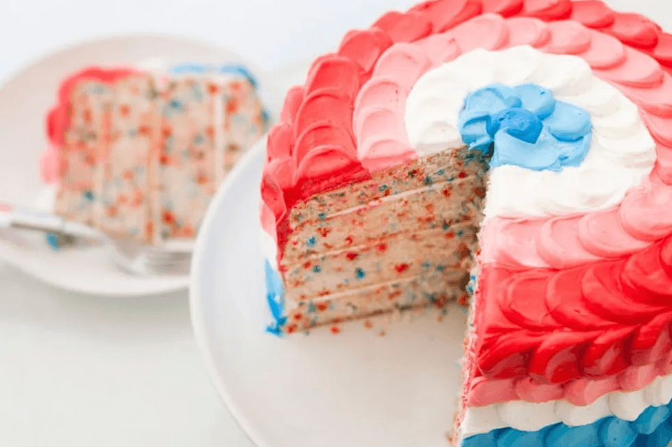 Colorful cake with red, white, and blue frosting and confetti sprinkles on a plate.