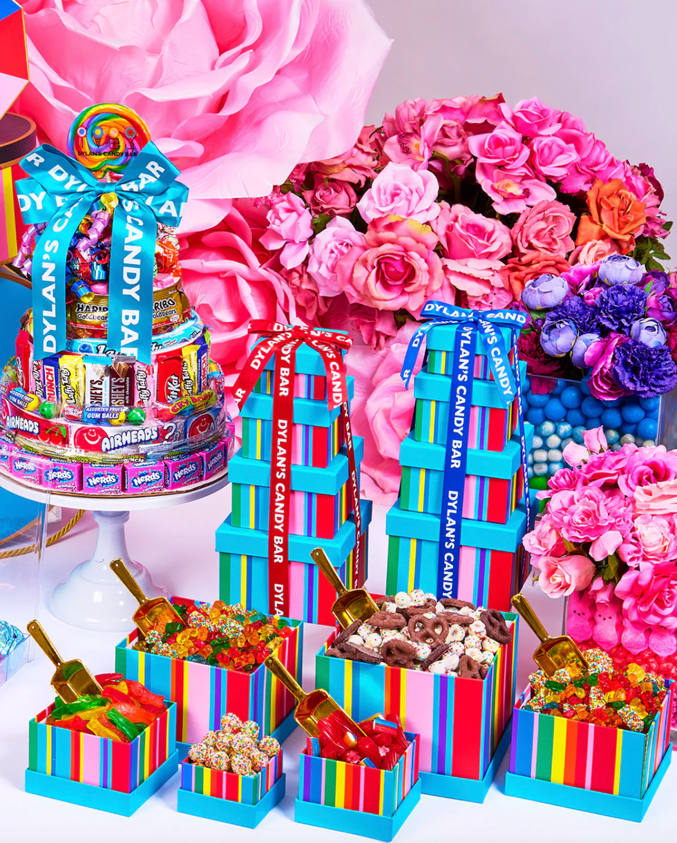 Colorful candy display with floral background and striped boxes, adorned with ribbons.