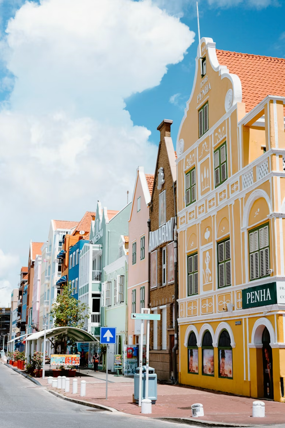 Colorful Dutch-style buildings under a bright blue sky with fluffy clouds.