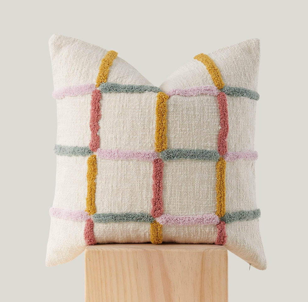 Colorful grid-patterned pillow on a wooden block with soft, textured fabric.