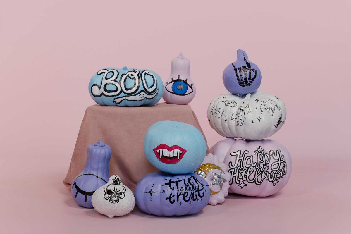 Colorful Halloween-themed pumpkins with painted designs on a pink background.