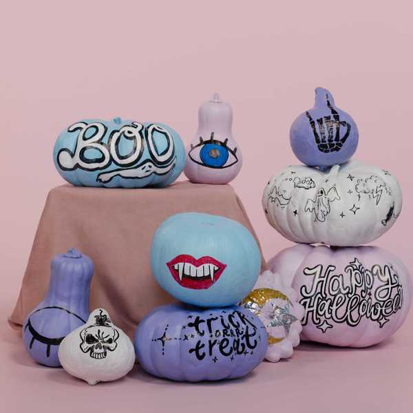 Colorful Halloween-themed pumpkins with painted designs on a pink background.