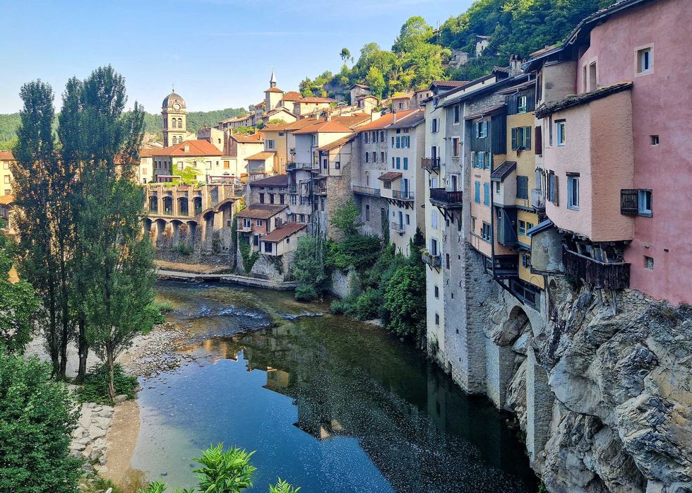 Colorful hillside village overlooking a serene river and lush greenery.