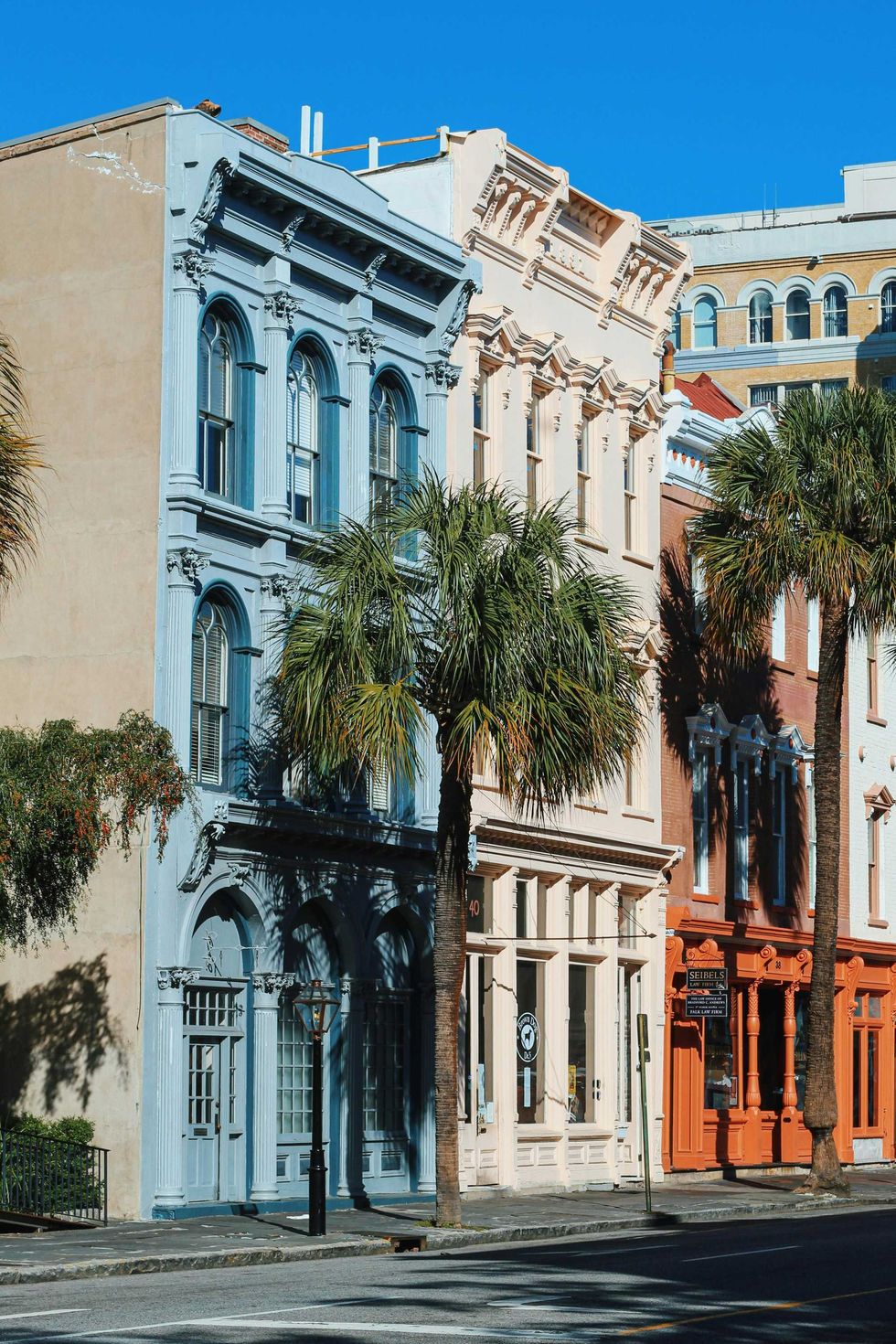 Colorful historic buildings with palm trees on a sunny street.