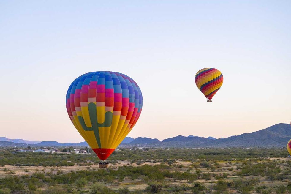 Colorful hot air balloons above a desert landscape with distant mountains.