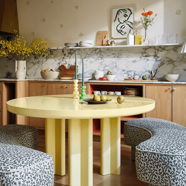 Colorful kitchen with yellow table, patterned stools, and marble backsplash.