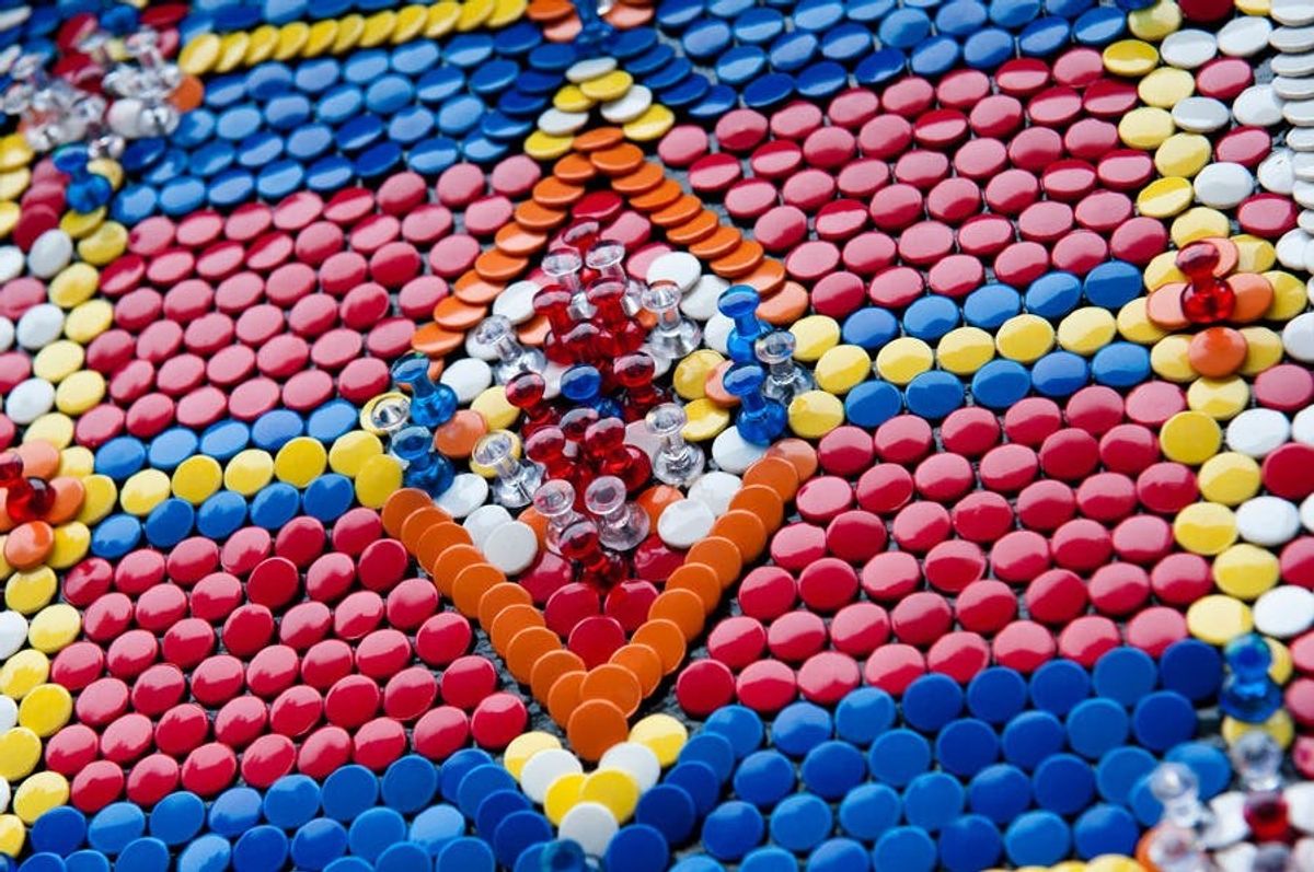 Colorful mosaic pattern with circular tiles and pushpins in red, blue, yellow, and orange.