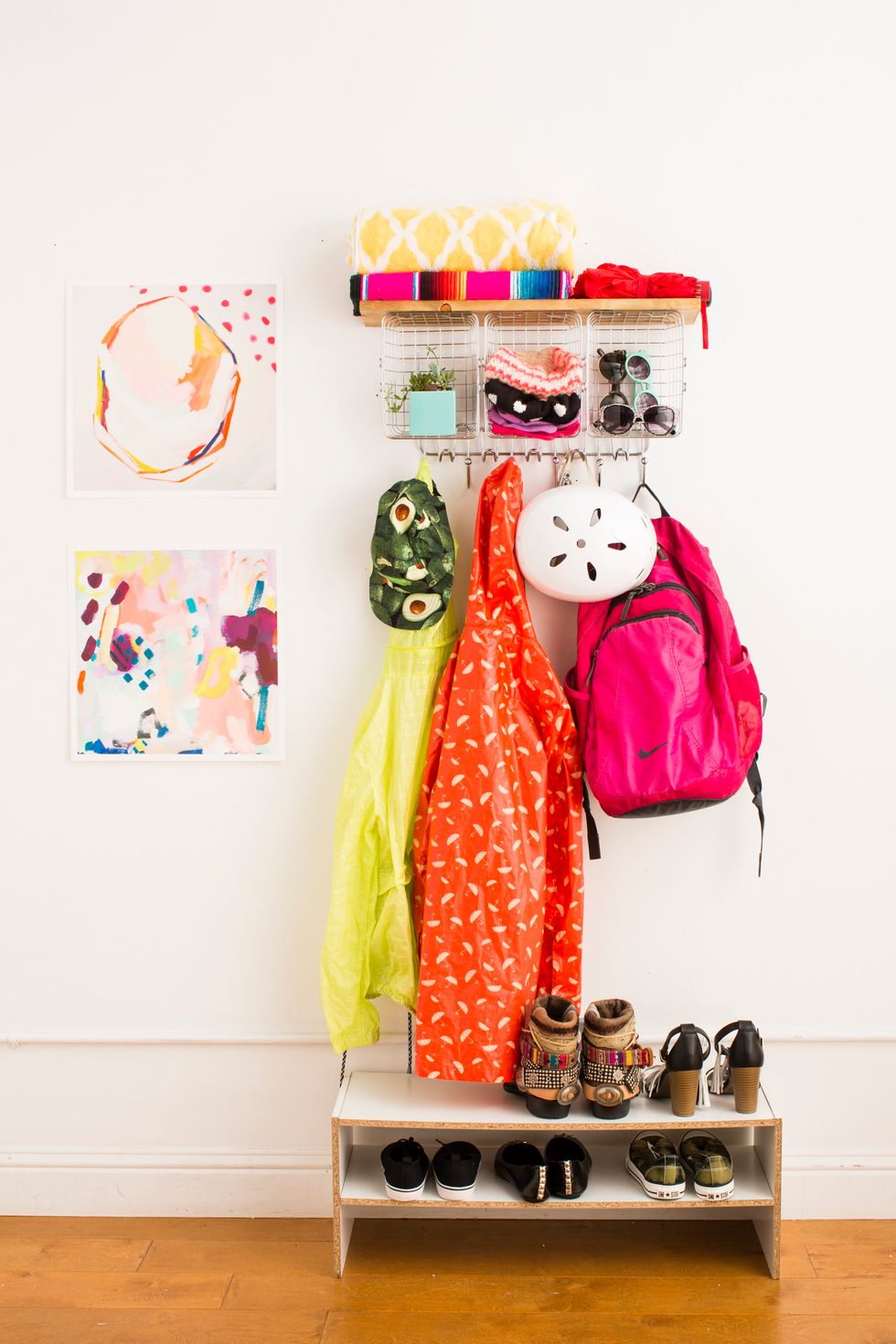 colorful outdoor accessories hanging on a diy rack in a mudroom beside rainbow artwork on the wall