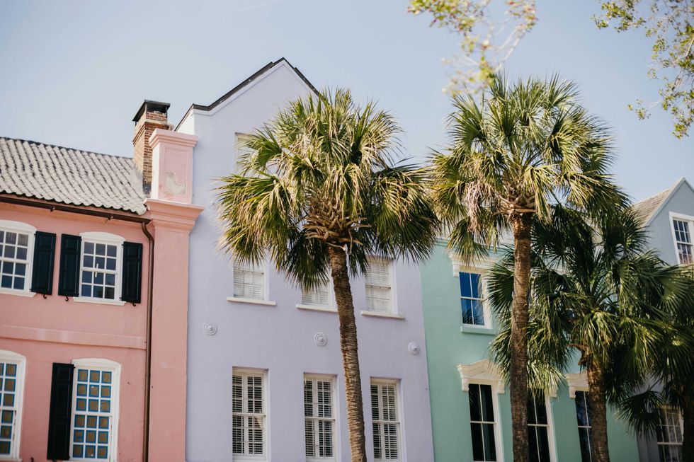 Colorful row houses and palm trees under a clear sky.