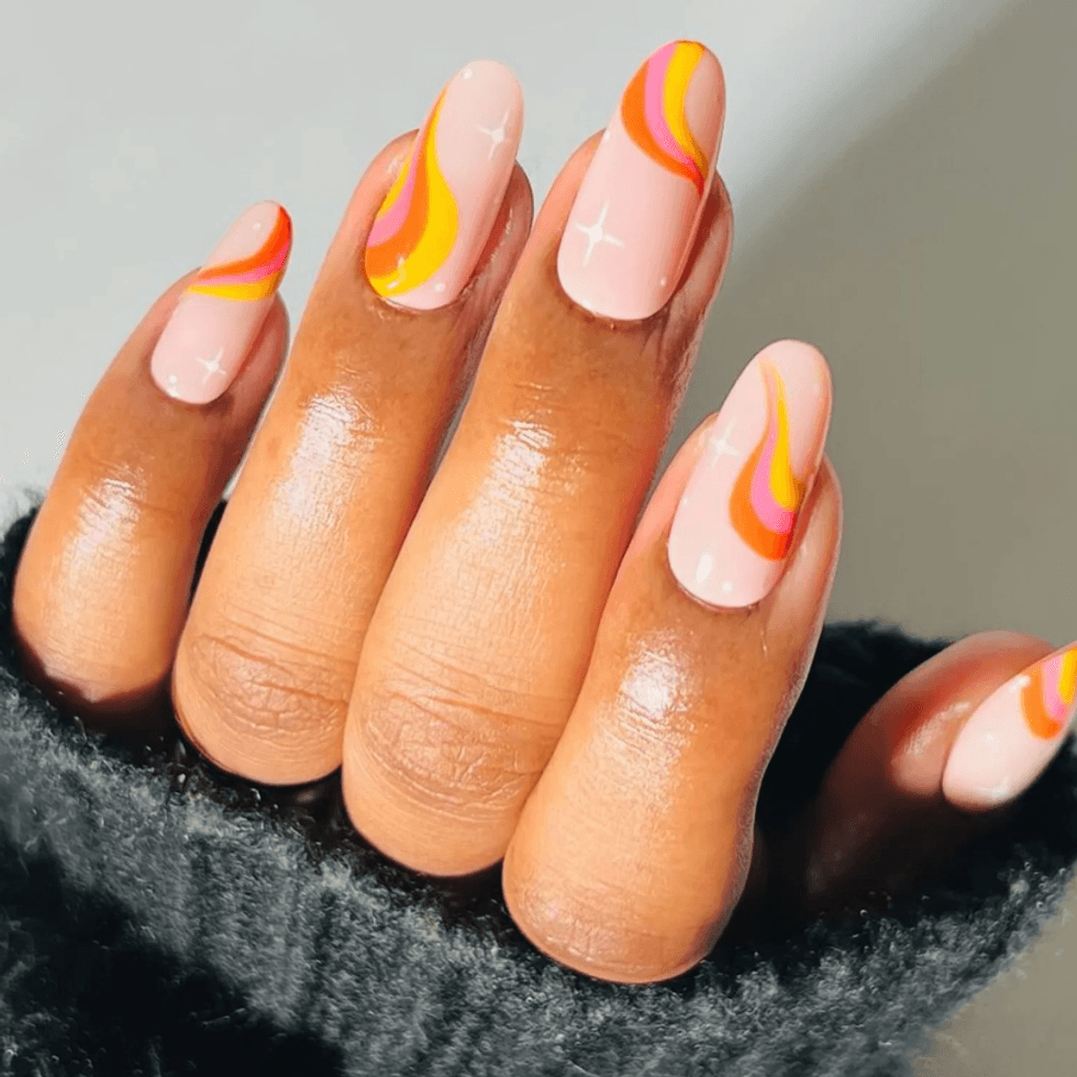 Colorful swirled nail art with pink, orange, and yellow lines on a hand.