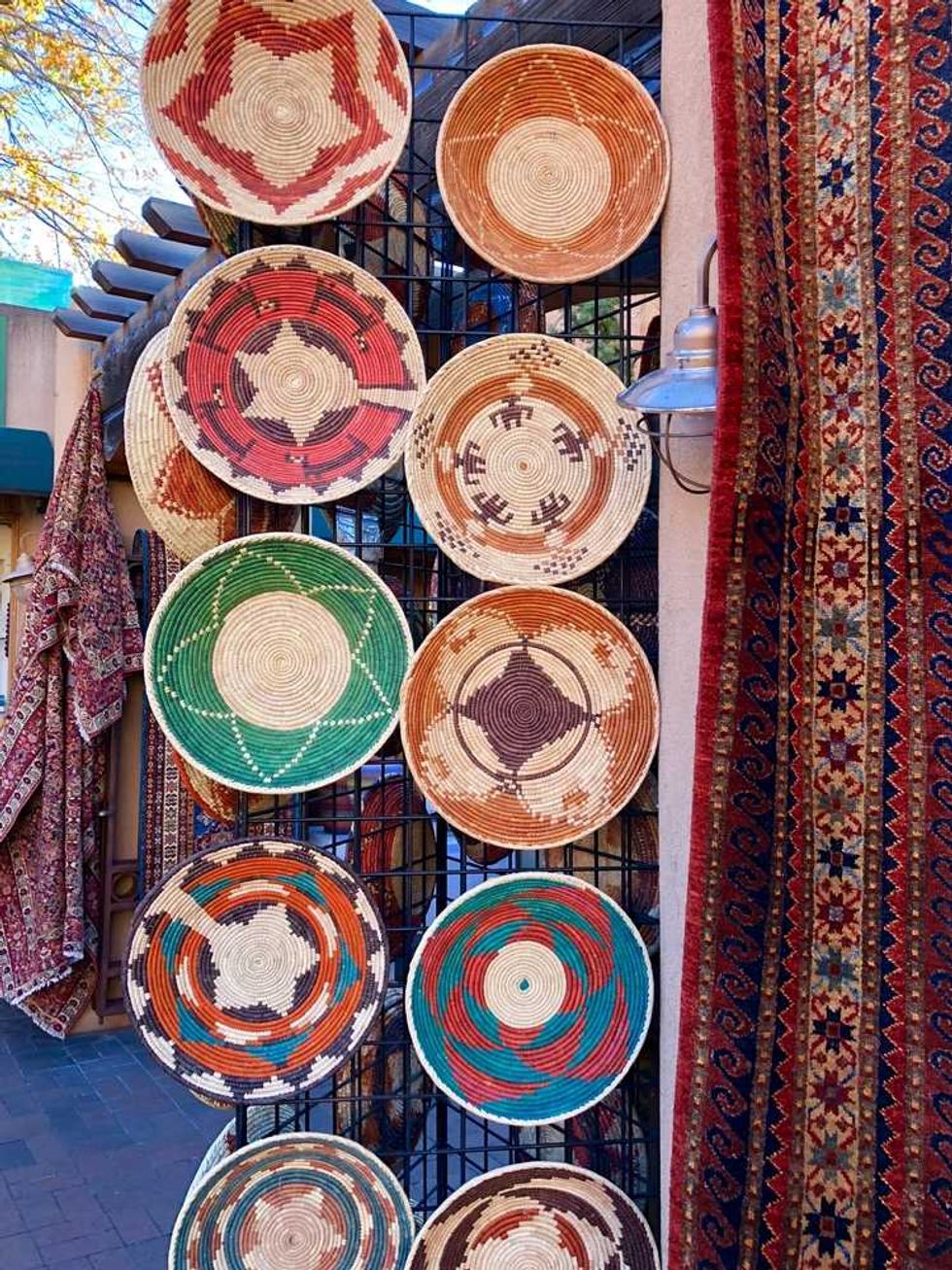Colorful woven baskets displayed on a grid, surrounded by patterned textiles.