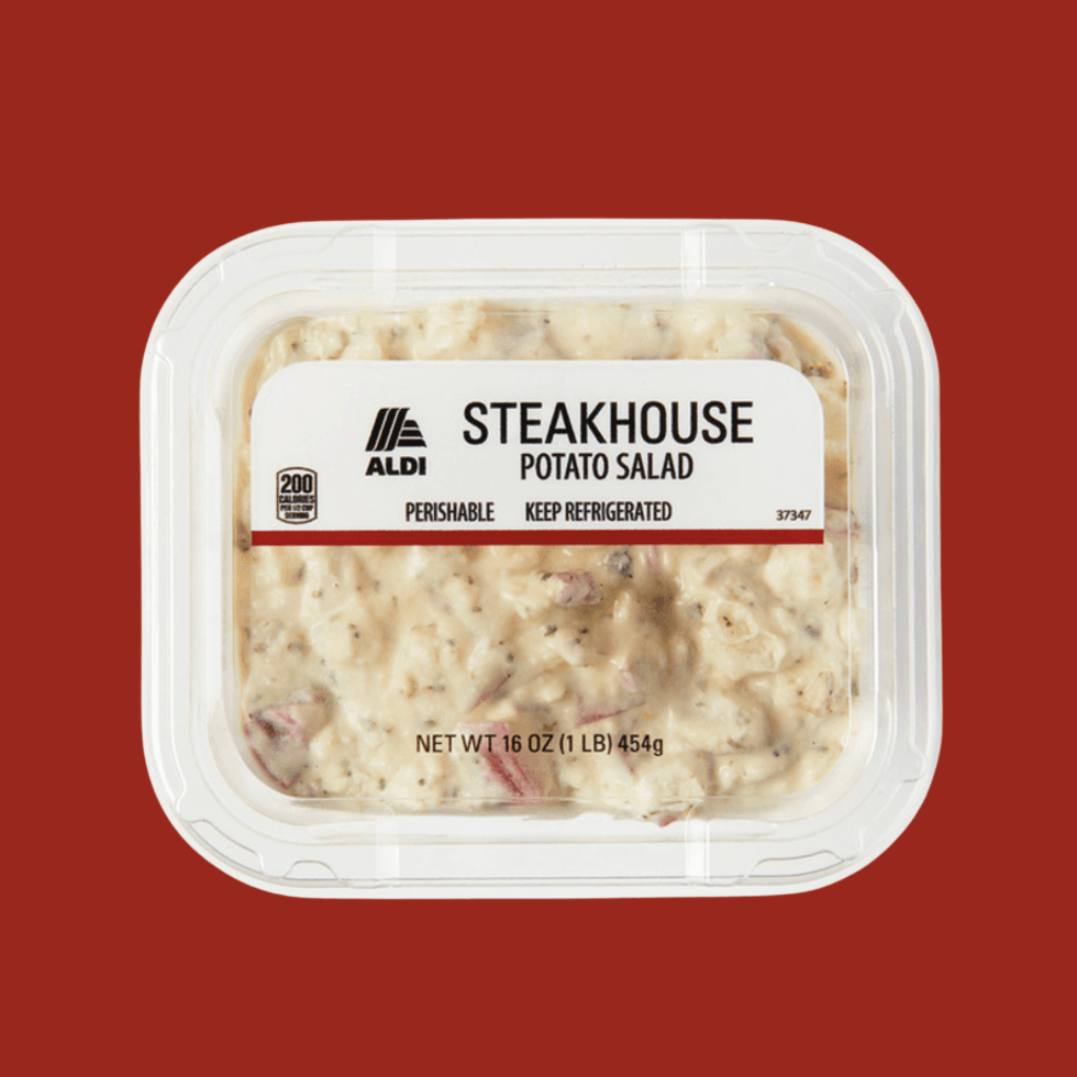 Container of Aldi Steakhouse Potato Salad on a red background.