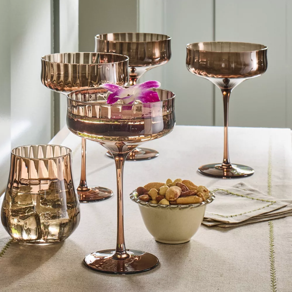 Copper-toned stemware and glass with nuts on a white table.