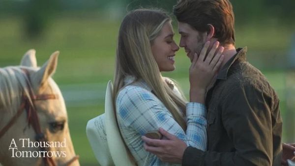 Couple embracing near a horse, smiling lovingly on a sunny day.