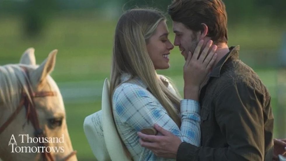 Couple embracing near a horse, smiling lovingly on a sunny day.