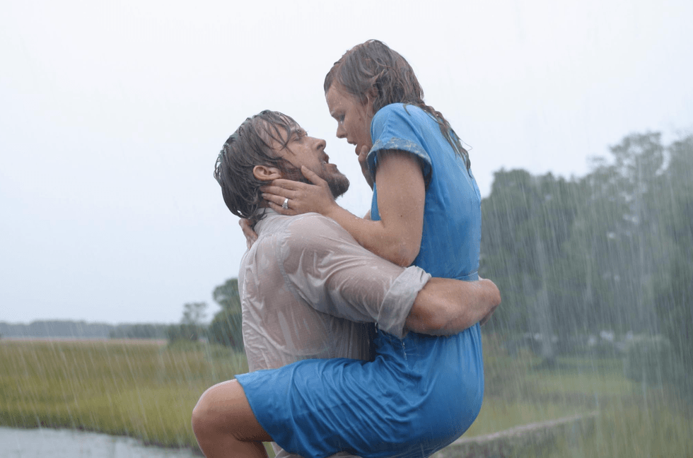 Couple embracing passionately in the rain with trees in the background.