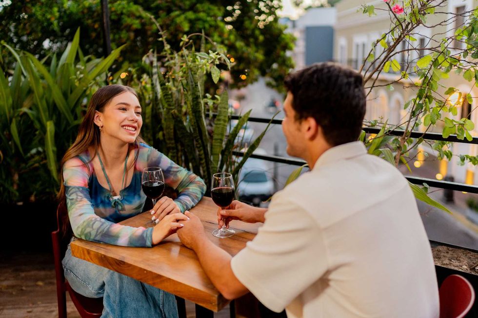 Couple enjoying a dinner date with wine on a leafy outdoor terrace.