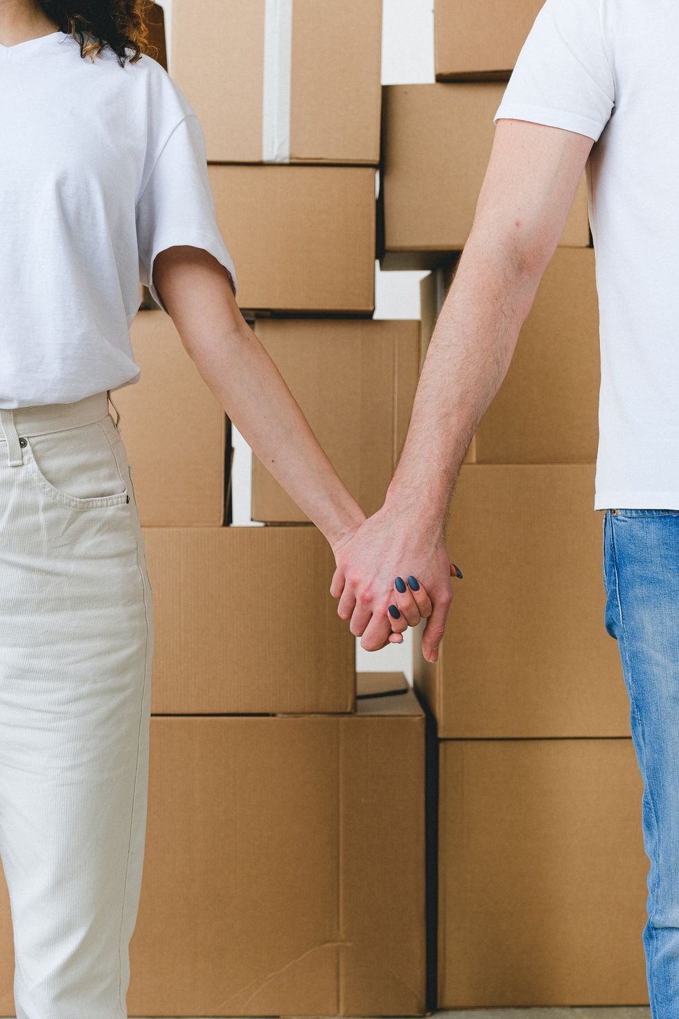 couple holding hands with moving boxes in the background