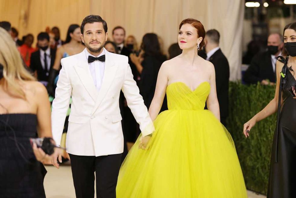 Couple in elegant attire, man in white tuxedo and woman in bright yellow gown.
