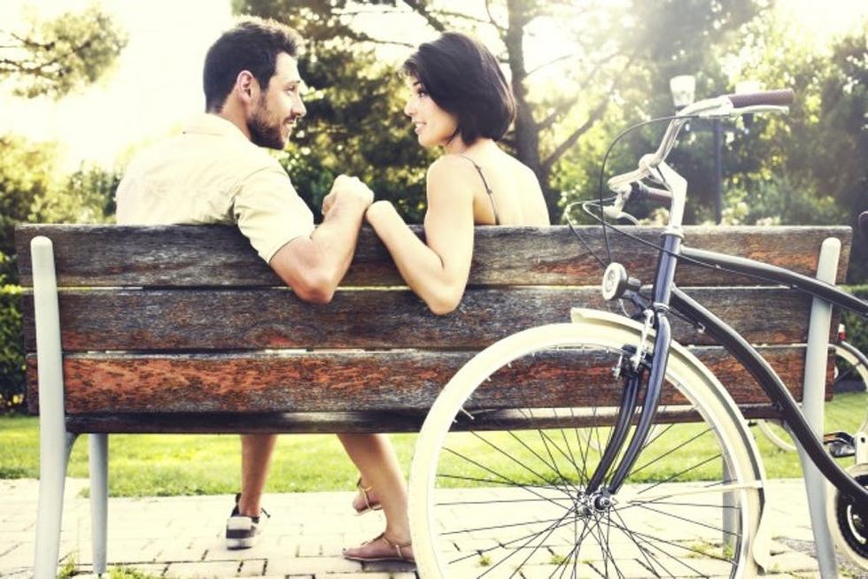 Couple in love sitted togheter on a bench with bikes