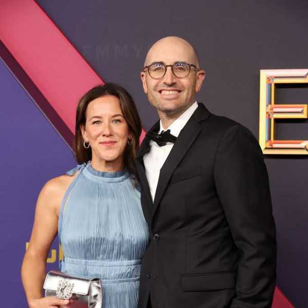 Couple posing elegantly on the red carpet in formal attire.