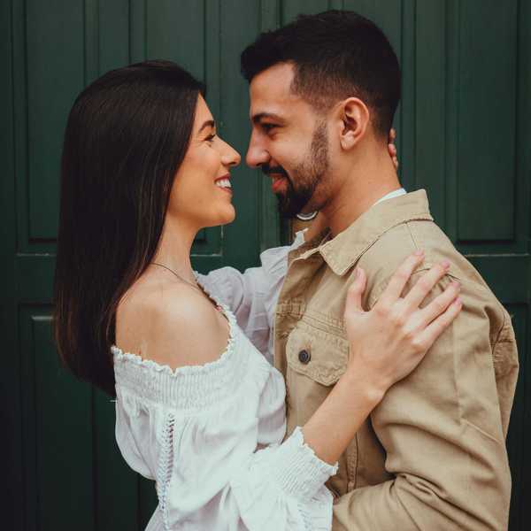 Couple smiling and embracing in front of a green door.