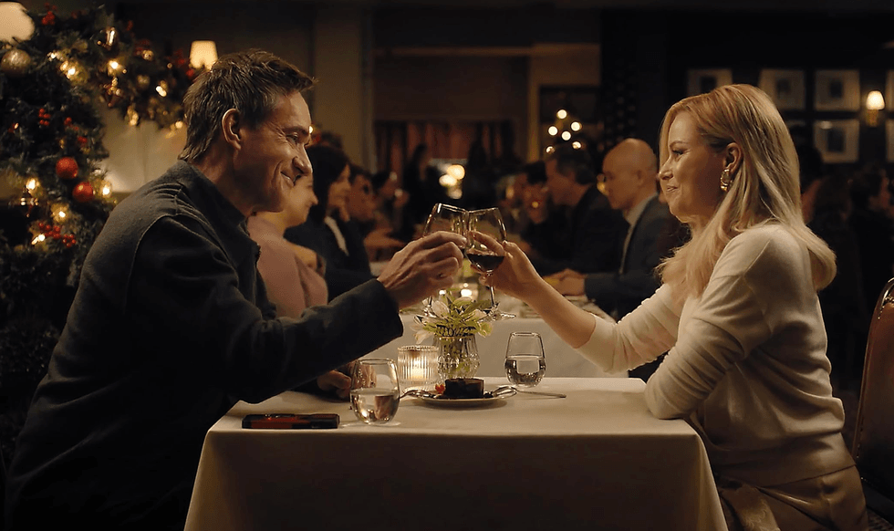 Couple toasting wine glasses at a cozy, festive restaurant table.