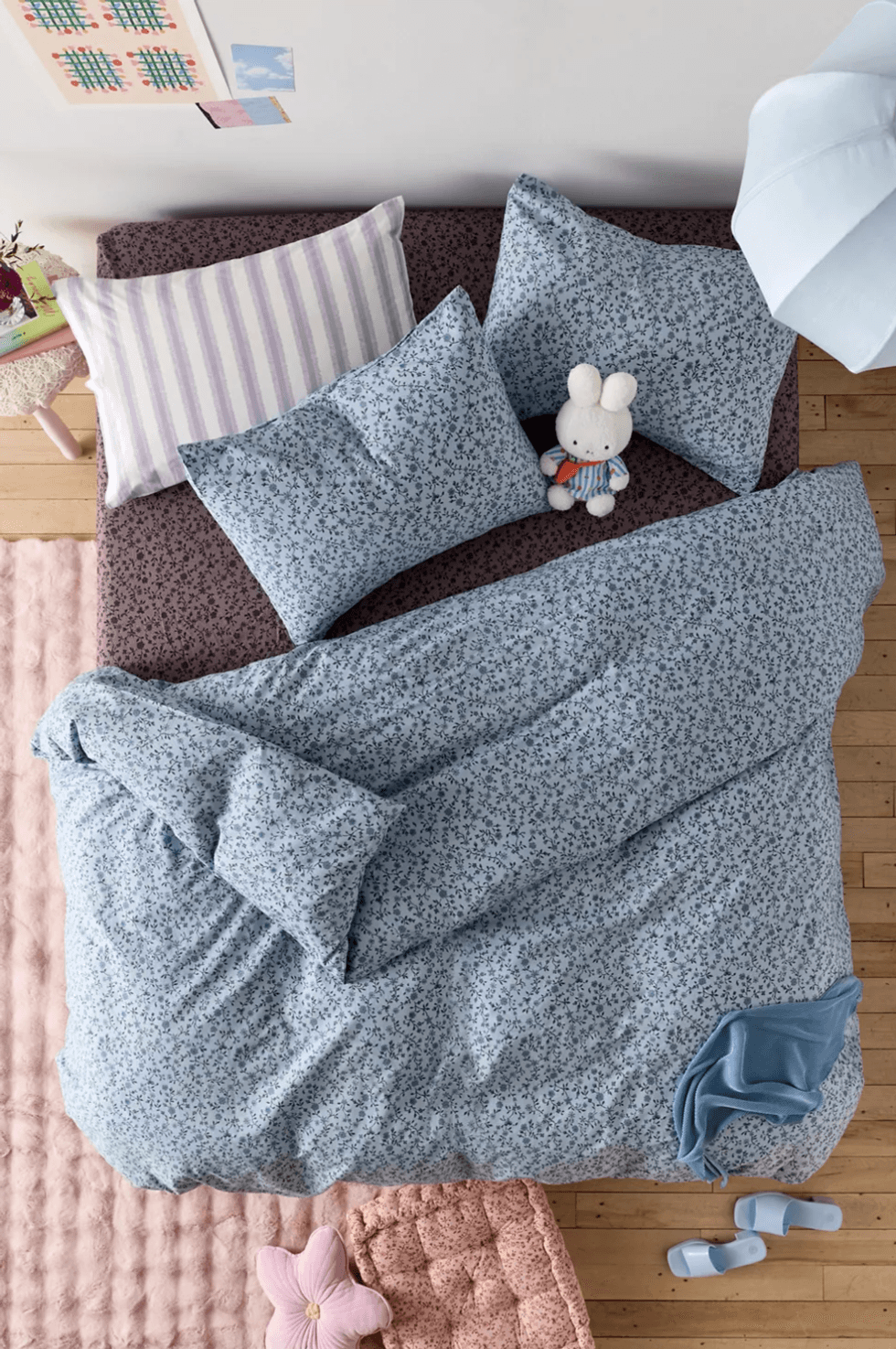 Cozy bed with blue floral sheets, stuffed bunny, and pastel decor accents.