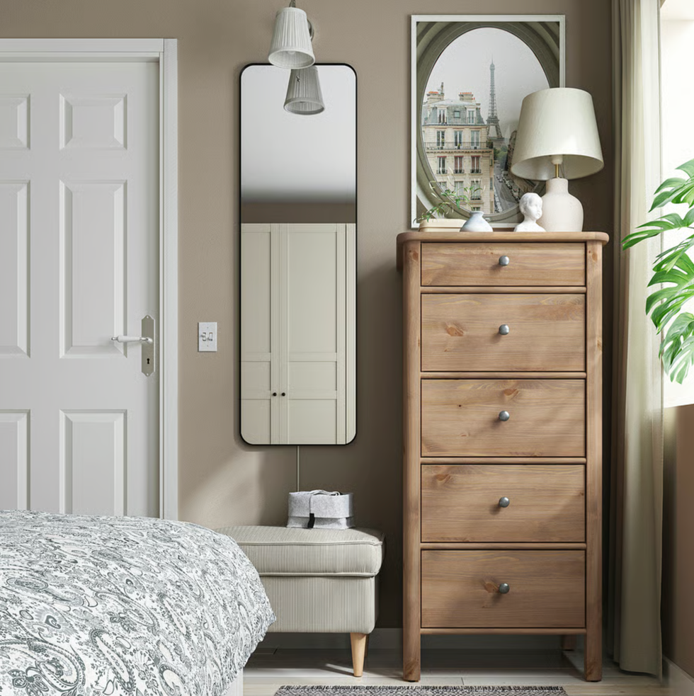 Cozy bedroom corner with tall wooden dresser, mirror, and elegant decor.