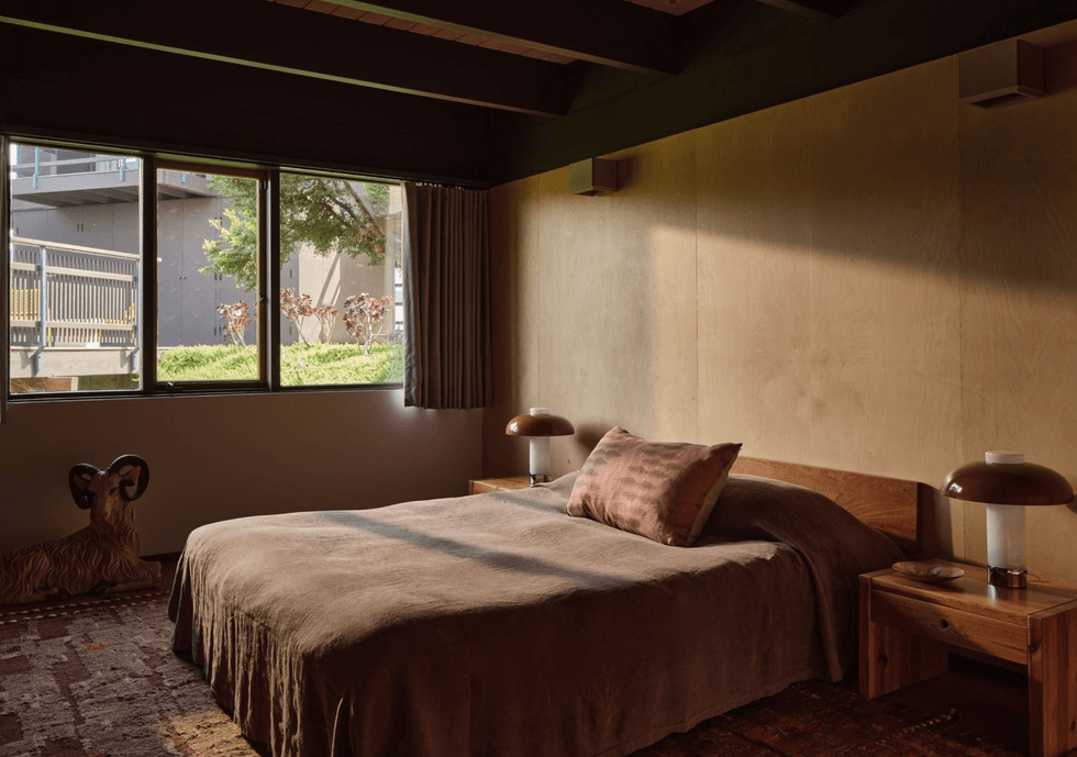 Cozy bedroom with brown decor, large window, and ram sculpture beside the bed.