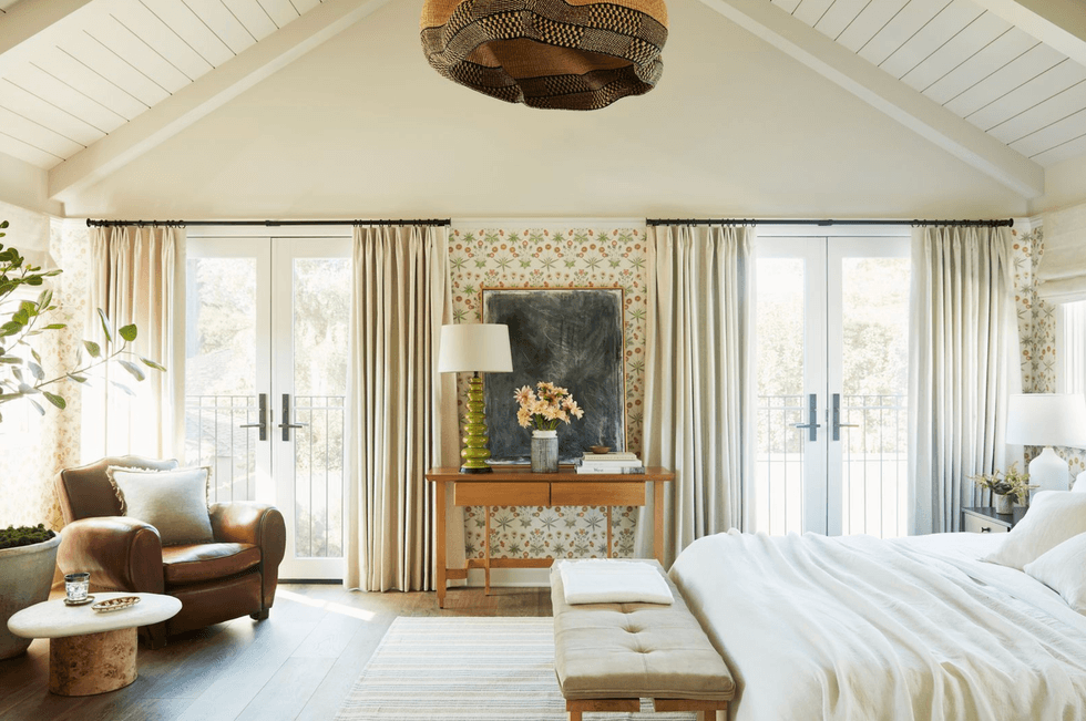 Cozy bedroom with French doors, floral wallpaper, and elegant decor elements.
