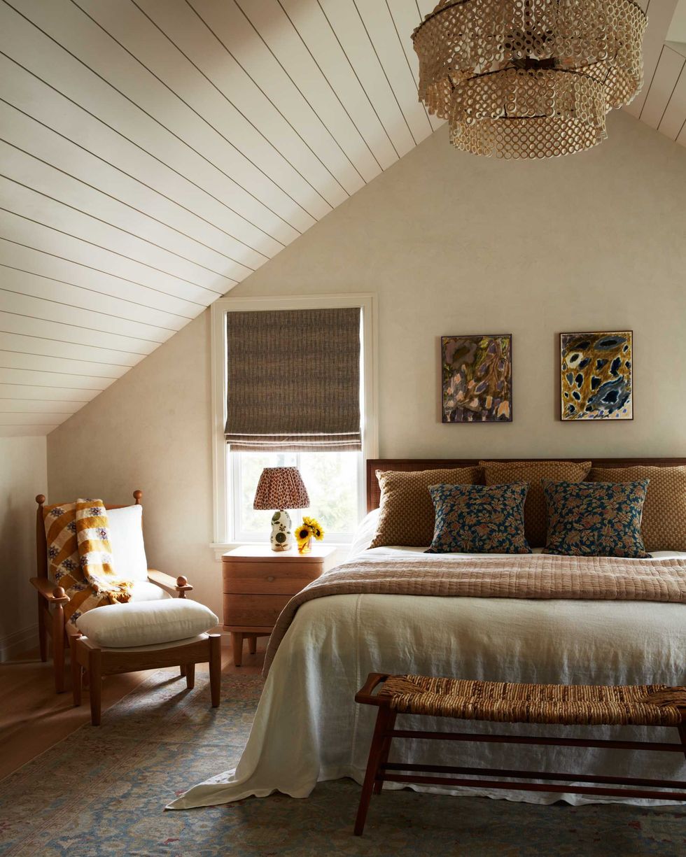 Cozy bedroom with slanted ceiling, floral decor, and warm lighting.