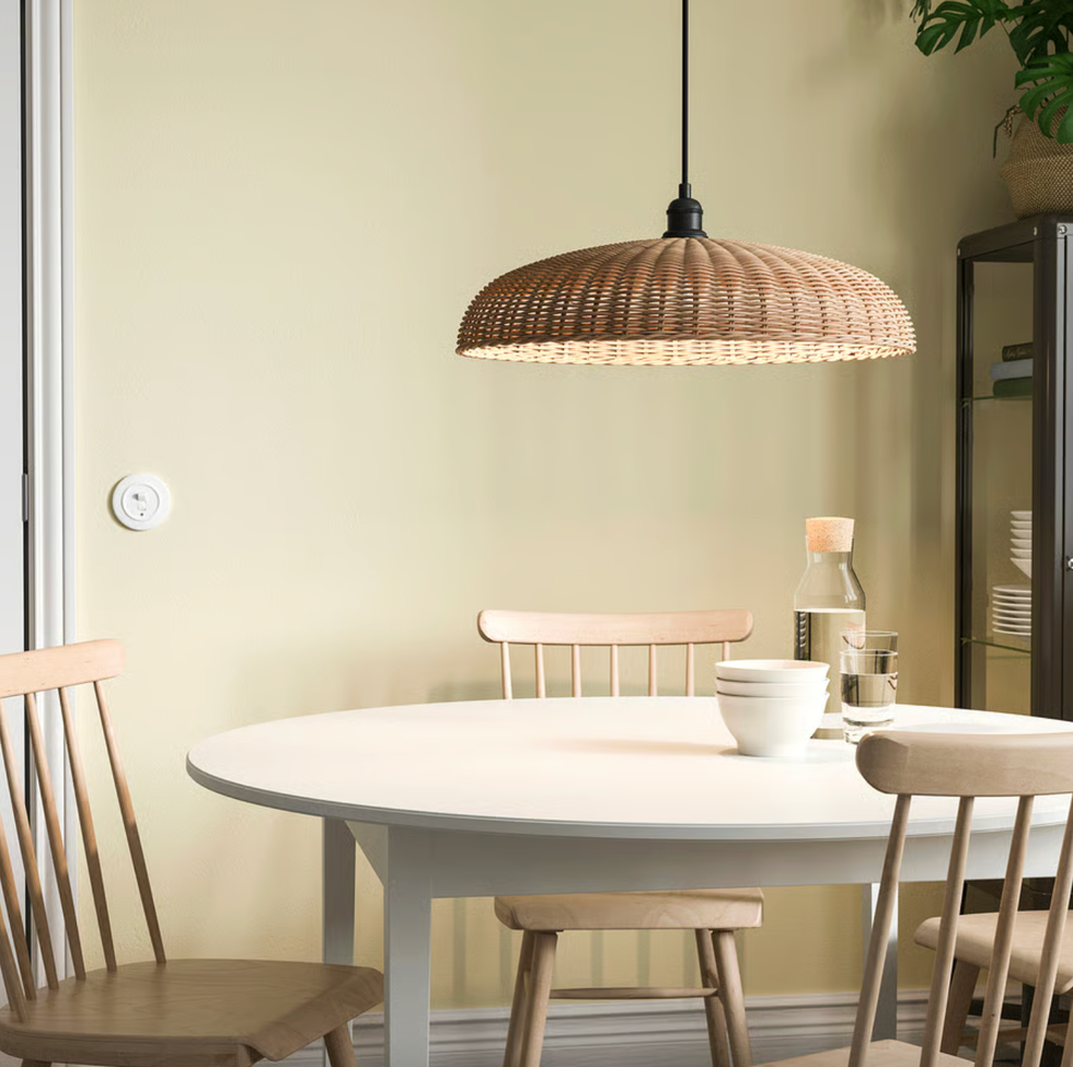 Cozy dining area with wicker pendant lamp, round table, and wooden chairs.