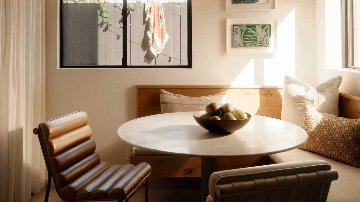 Cozy dining nook with round table, leather chairs, large window, and overhead light fixture.