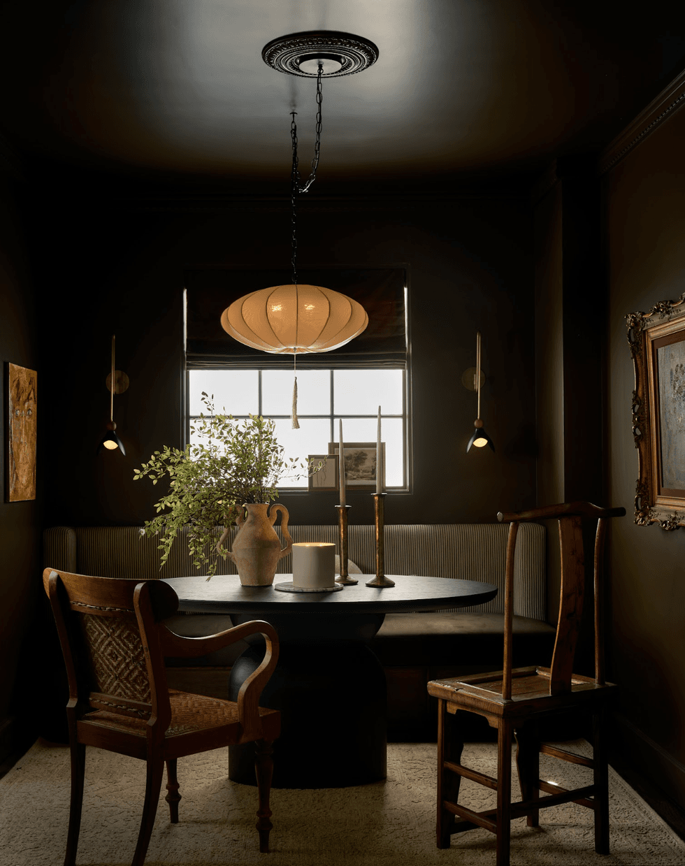 Cozy dining nook with round table, two chairs, pendant light, and rustic decor.