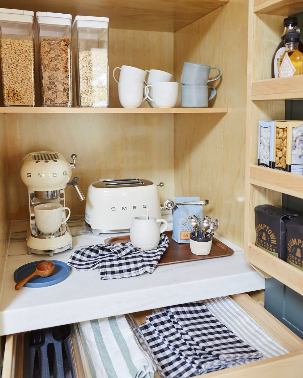 Cozy kitchen nook with a Smeg coffee maker, toaster, and organized shelves of mugs and cereal.
