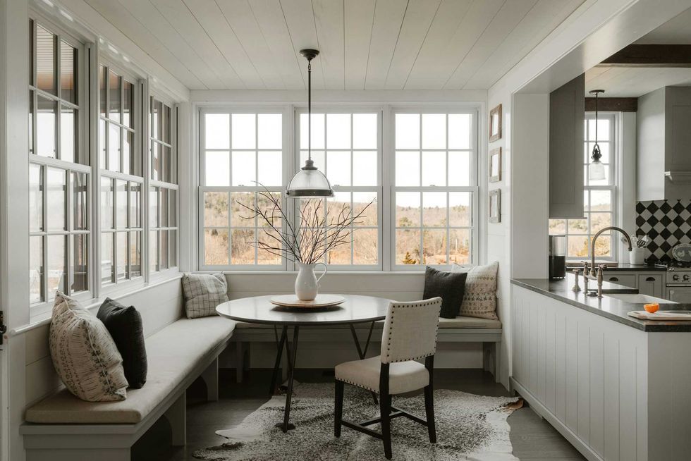 Cozy kitchen nook with table, chairs, large windows, and neutral decor.