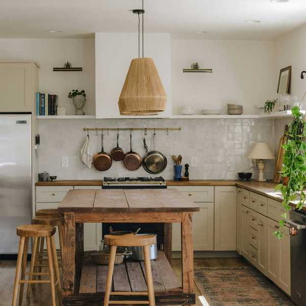 Cozy kitchen with hanging pendant light, wooden island, and potted plant on counter.