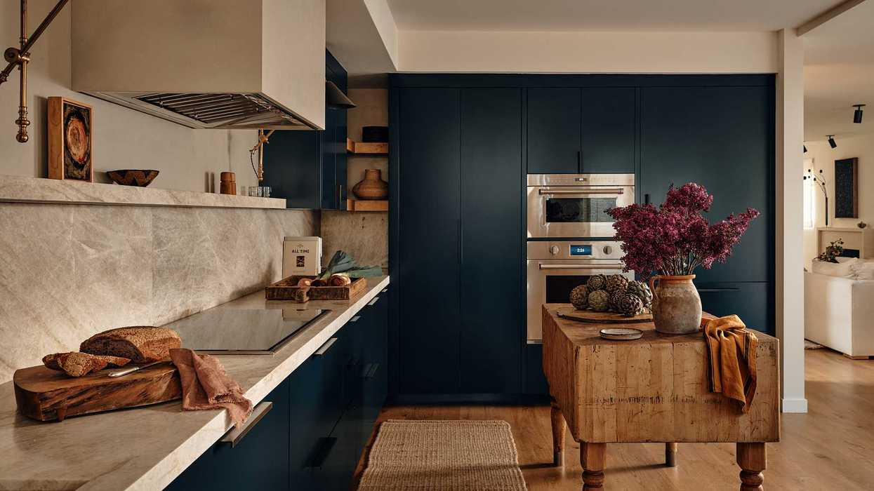 Cozy kitchen with wood and marble accents, an island with flowers, and modern appliances.