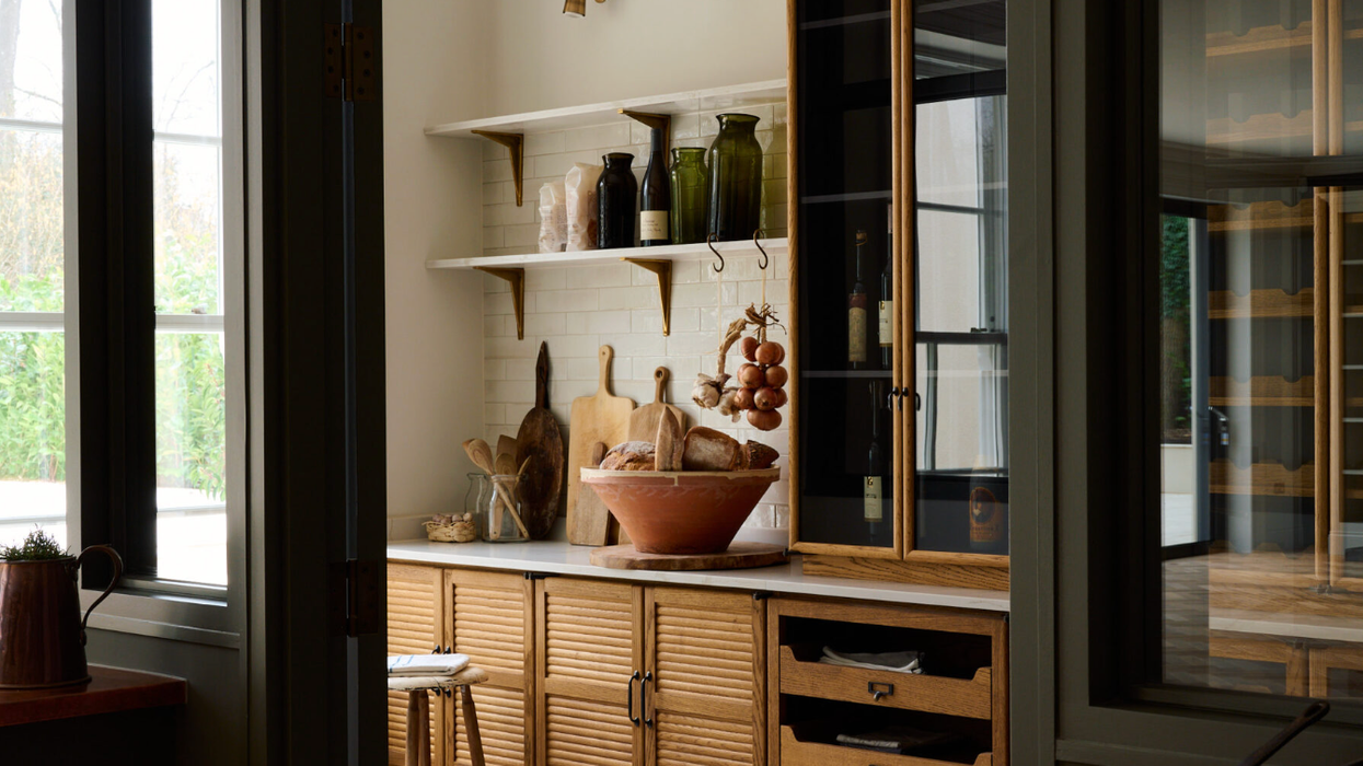 Cozy kitchen with wooden cabinets, open shelves, and decorative jars on a patterned floor.