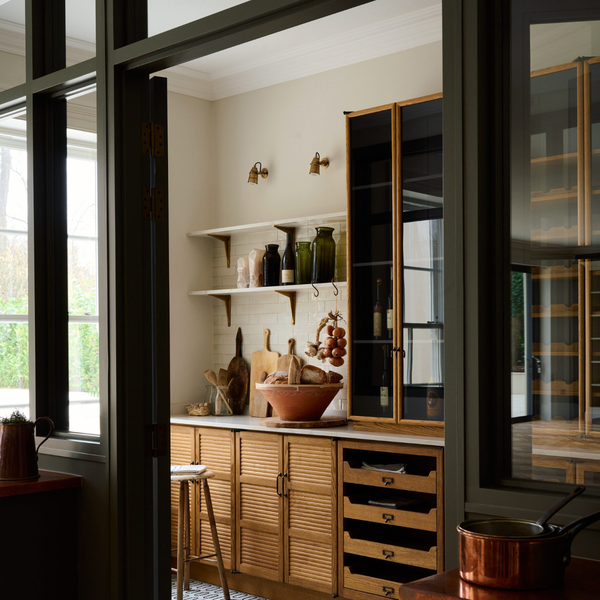 Cozy kitchen with wooden cabinets, open shelves, and decorative jars on a patterned floor.