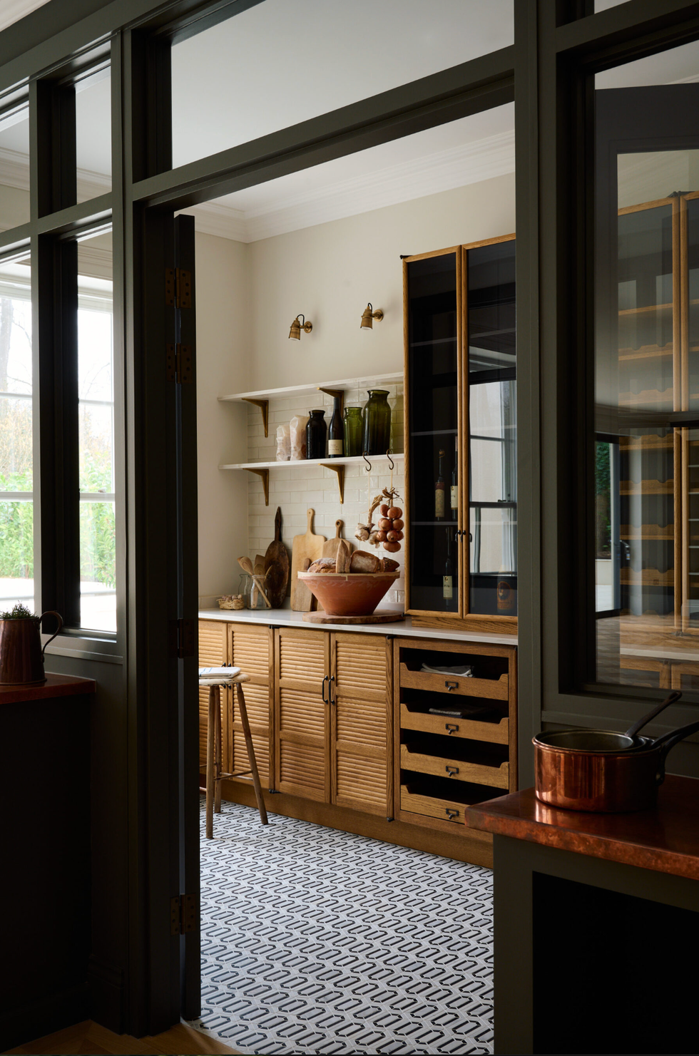 Cozy kitchen with wooden cabinets, open shelves, and decorative jars on a patterned floor.