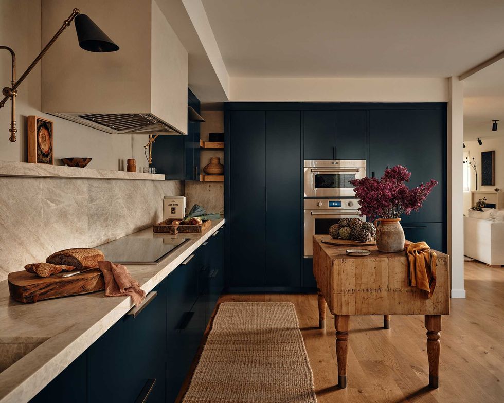 Cozy kitchen with wooden furnishings, rustic decor, and a vase of purple flowers on a butcher block.