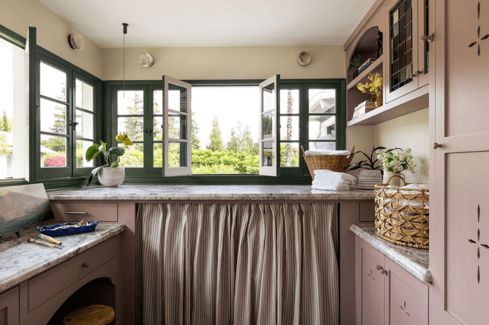 Cozy laundry room with mauve cabinets and open windows showcasing a lush garden view.