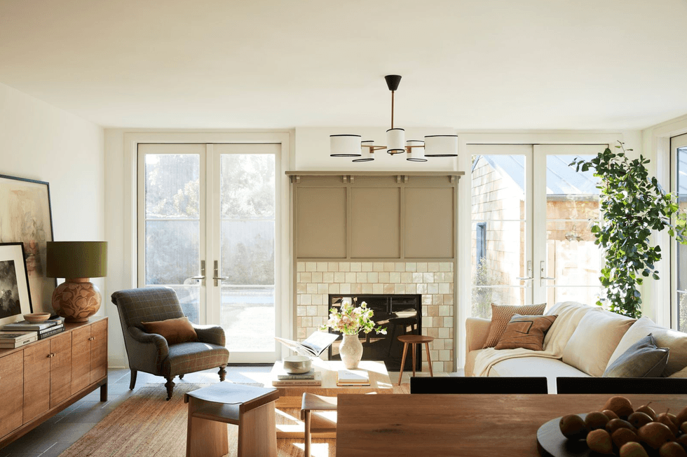 Cozy living room with a beige sofa, armchair, fireplace, and large windows.