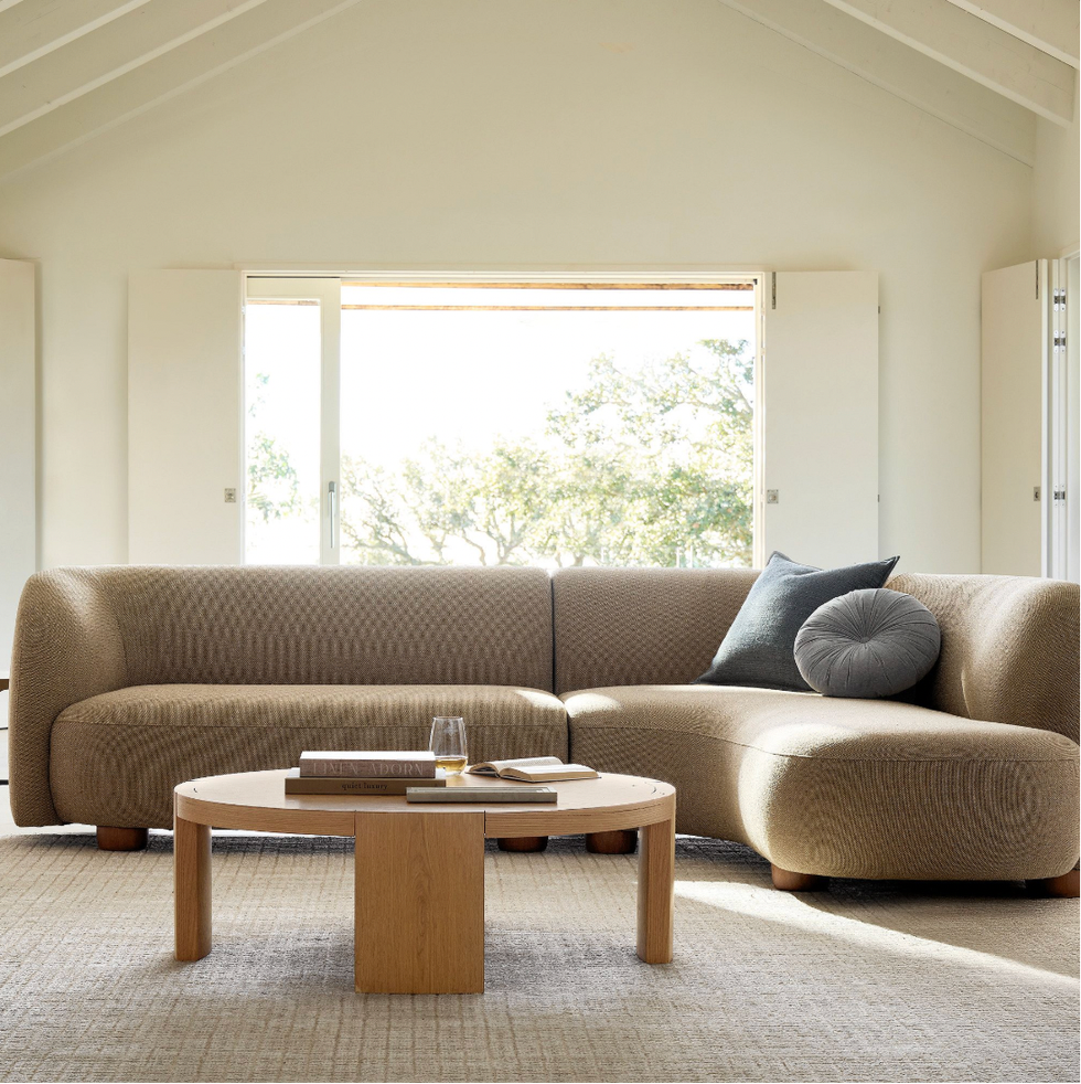 Cozy living room with a brown sectional sofa, wooden coffee table, and large window view.