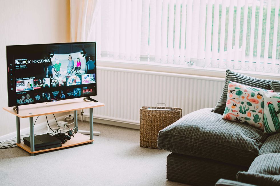 Cozy living room with a TV, gray couch, and colorful cushions.