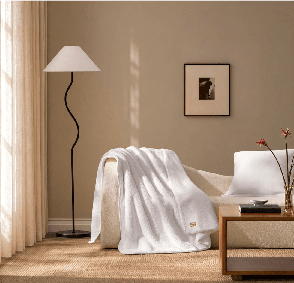 Cozy living room with a white blanket on a sofa, a lamp, and wall art.